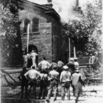 Firemain attempt to extinguish the Turner Hall fire while onlookers observe